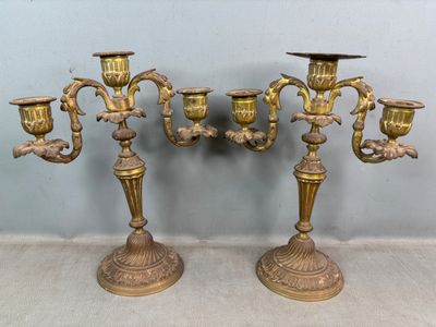 une paire de chandeliers anciens en laiton, ornés chacun d'un oiseau