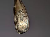 a silver spoon with a picture on it hanging from a hook