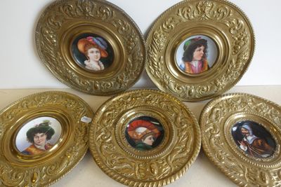 quatre assiettes en or ornées de portraits, posées sur une table