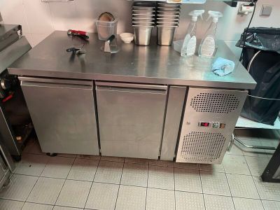 un plan de travail en acier inoxydable dans une cuisine, sur lequel sont posées des casseroles et des poêles
