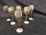 quatre verres à vin argentés à pied sur fond noir
