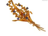 une image représentant une broche en or ornée de pierres bleues