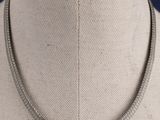 collier en métal argenté, au motif incurvé, posé sur le cou d'un mannequin