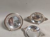 trois plats en métal argenté posés sur une table, avec un miroir au milieu