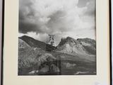 photographie en noir et blanc d'un phare au milieu d'une chaîne de montagnes