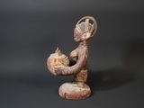 statue of a woman holding a bowl of food on a black background