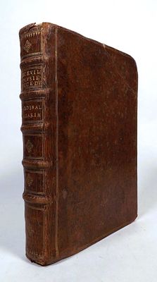 an old brown book sitting on top of a table next to a white wall