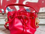 red leather bucket bag with gold hardwares on a concrete surface