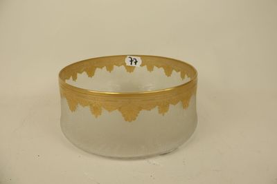 a glass bowl with a gold rim on a white surface
