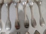 de nombreuses cuillères et fourchettes disposées sur une table