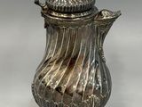an antique silver coffee pot with a lid on a stand