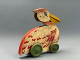 a wooden bird sitting on top of a toy car