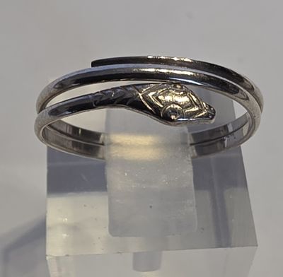 une bague en argent ornée d'un serpent, posée sur une surface transparente