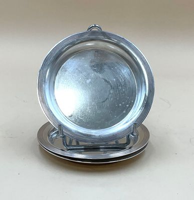 une assiette en argent posée sur un porte-assiette en argent, sur une table