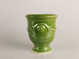 a green vase with a face on it on a table