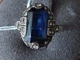 a ring with a blue stone in it sitting on a cushion