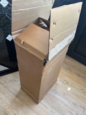 une boîte en carton posée par terre à côté d'un réfrigérateur