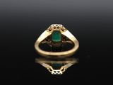 a gold ring with an emerald stone in the center