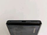 the back of a black cell phone sitting on top of a white table