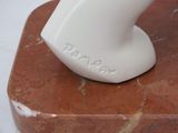 a white vase sitting on top of a red marble block