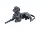 statue of a black dog laying down on a white surface