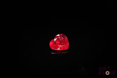 un gros plan d'un diamant rouge en forme de cœur sur une surface noire