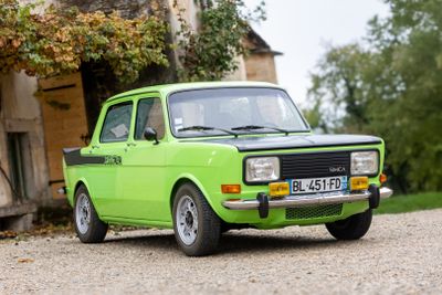 une petite voiture verte garée devant une maison