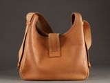 a close up of a brown leather bag on a gray surface