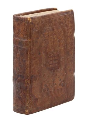 un vieux livre à la couverture brune posé sur une surface blanche