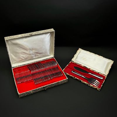 des couverts dans un coffret en argent doublé de velours rouge, posé sur un fond noir