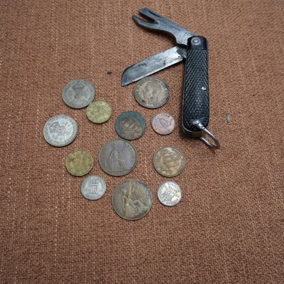 un couteau de poche et quelques pièces de monnaie posés sur une table