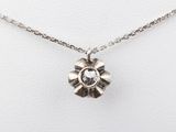 a close up of a silver necklace with a flower on it