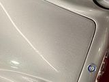 a small white car with a blue emblem on the hood