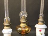 three antique oil lamps are lined up against a black background