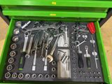 a green tool box with tools in it on the floor