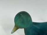 a blue glass duck sitting on a white surface