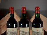 two bottles of red wine sitting on top of a wooden crate