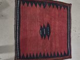 un vieux tapis rouge et noir posé sur un sol blanc