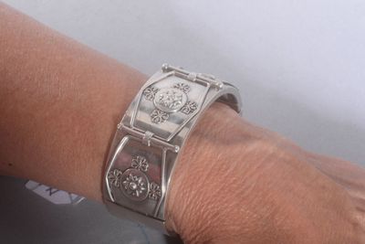 a woman ' s hand with a silver bracelet on it