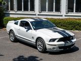 a white mustang parked in a parking lot next to a building