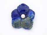 une fleur bleue contenant une perle, sur un fond blanc