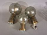 three silver and gold light bulbs on a white surface
