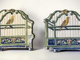 two small bird cages with birds in them on display