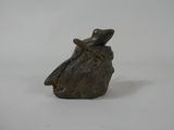 figurine of a frog sitting on a rock on a white background