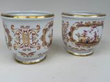 pair of white and gold vases with designs on them on a white surface