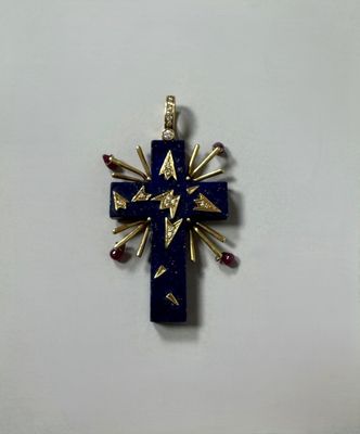 un gros plan d'une croix sur une surface blanche, ornée de pierres rouges et bleues