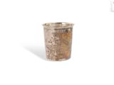 une tasse en argent posée sur une surface blanche