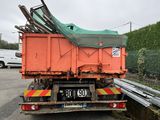 a large orange truck with a green tarp on the back of it