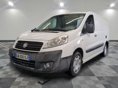 La petite camionnette blanche est garée dans une grande pièce au sol carrelé en damier.