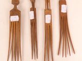 three wooden hair combs are lined up on a white surface